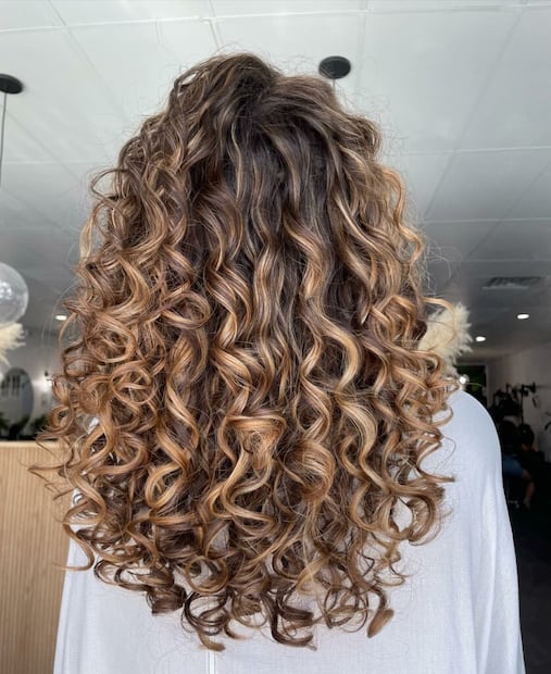 Curly balayage: aclarado degradado que ilumina rizos sin perder definición. Foto: Instagram @curlssbyylexx