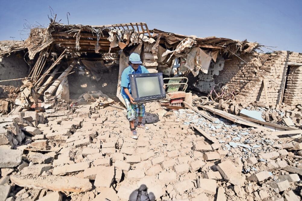 Un hombre de la localicad de Acari, en Arequipa, rescata algunas de sus pertenencias de los restos de su casa que fue destruida por el temblor que se registró ayer en el sur de Perú. (DIEGO RAMOS. REUTERS)