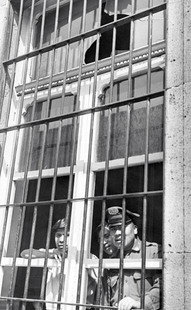Algunos agentes de seguridad pública se resguardan tras los barrotes, luego de que un grupo de estudiantes lanzara piedras a la comandancia local. Foto: ESPECIAL.