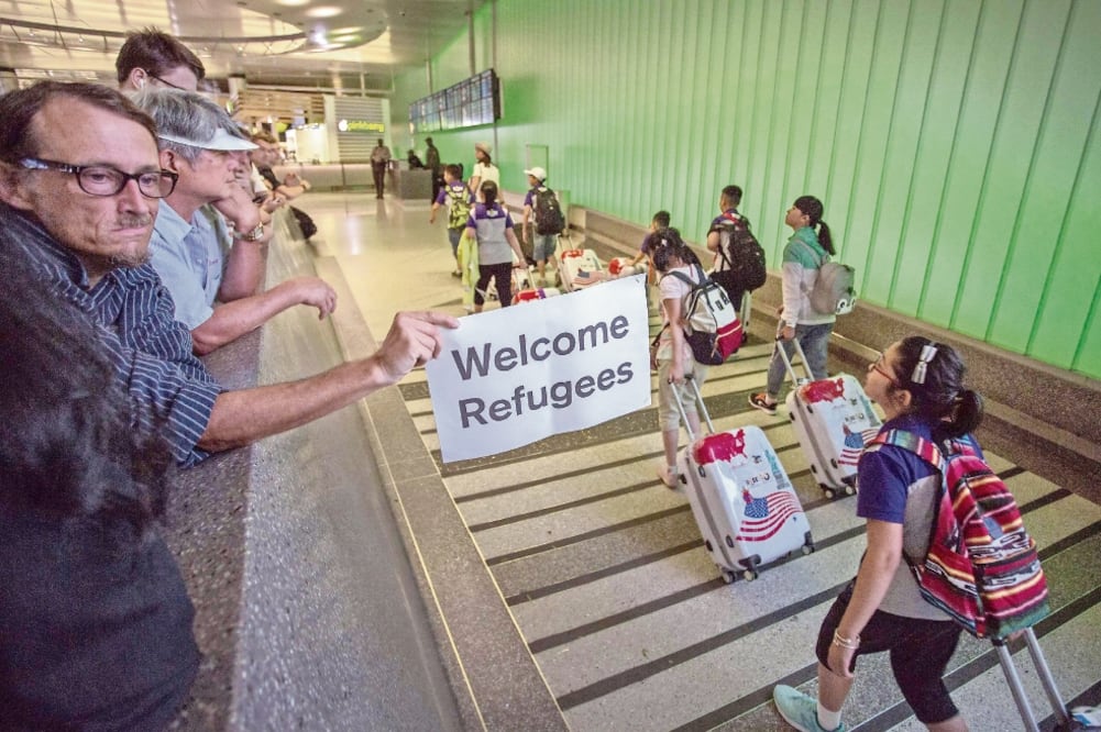 John Wider porta un letrero de bienvenida a los refugiados, ayer, en el aeropuerto de Los Ángeles, al entrar en vigor parcialmente el veto migratorio. Foto: Archivo/El Universal