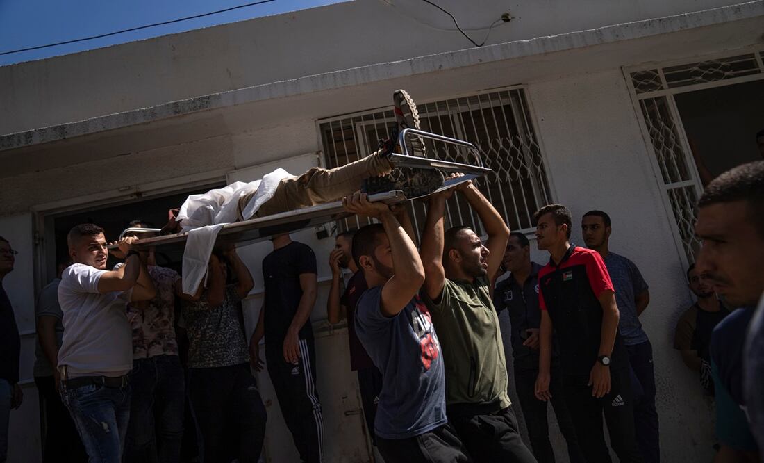 Palestinos cargan el cuerpo de un hombre muerto durante los combates con las fuerzas israelíes, en la ciudad de Gaza, el sábado 7 de octubre de 2023. Foto: AP