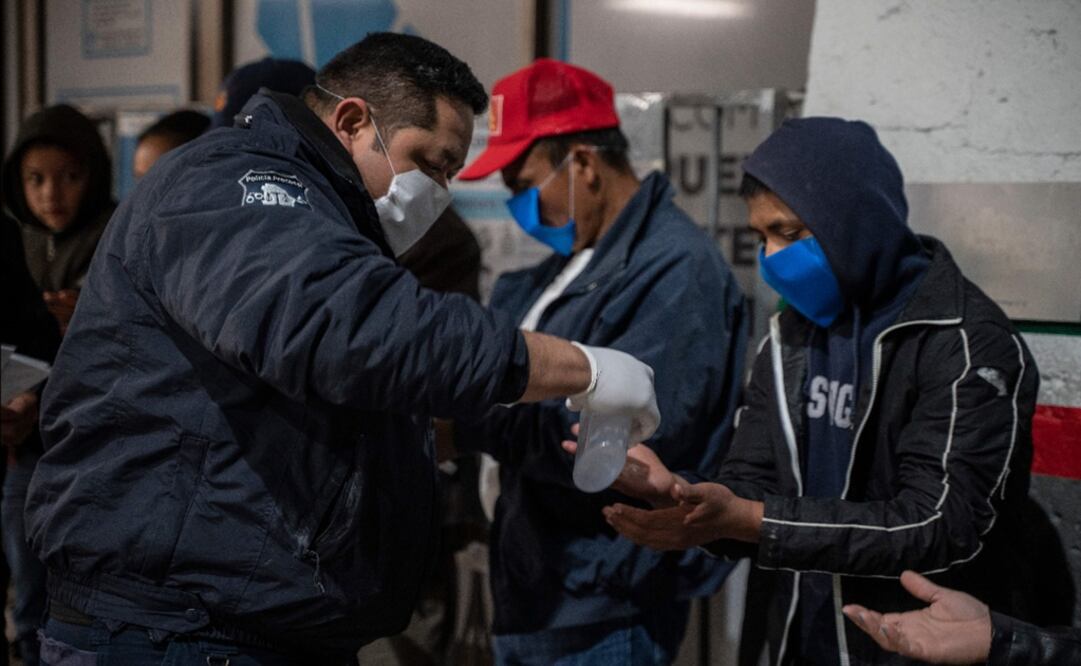 A Mexican police officer gives out hand sanitizer to migrants – Photo: Paul Ratje/AFP	