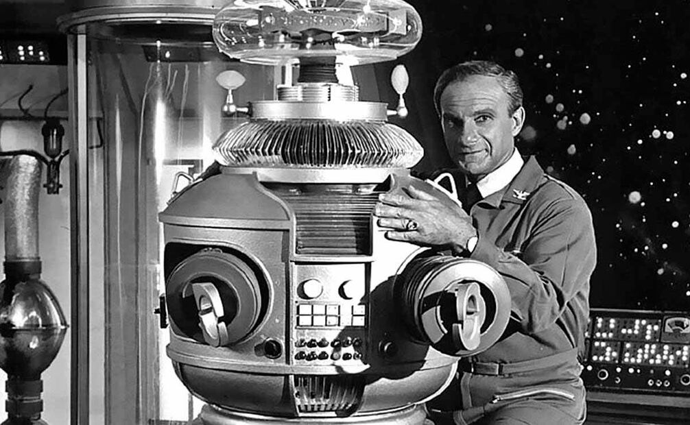 Foto del actor Jonathan Harris interpretando a uno de los científicos que acompañan a la familia Robinson en la serie de televisión de “Perdidos en el espacio”. Uno de los acompañantes de los tripulantes era una máquina dotada de fuerza sobrehumana y armamento futurista que mostraba expresiones humanas, como risas, sonidos de tristeza y burlas, además cantaba y tocaba la guitarra. Foto: CBS Television Photo Archive, Wikimedia commons/ Especial.