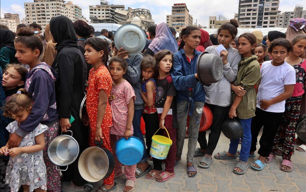 Palestinos, en su mayoría niños, hacen fila frente a un camión de reparto de comida caliente en un campamento de desplazados cerca del puerto de la Ciudad de Gaza, el 22 de mayo de 2025. Foto: AFP
