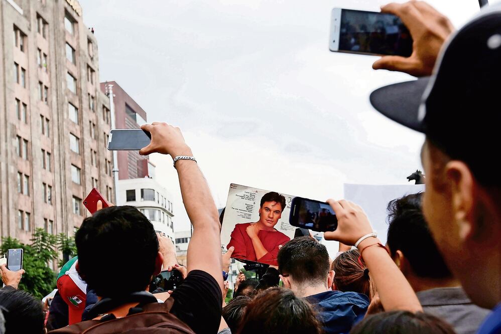 Aunque fuera de lejos, todos alzaban sus teléfonos celulares para captar la carroza donde iban los restos de Juan Gabriel (CARLOS JASSO. REUTERS)