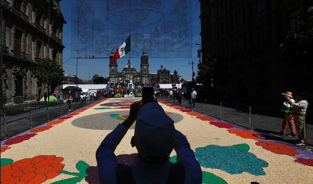 Visitantes toman fotos del tapete monumental que para su elaboración se requirieron entre 2 y 2.5 toneladas de material y un equipo de 12 personas, en el Zócalo capitalino, el 27 de octubre de 2025. Foto: Berenice Fregoso/EL UNIVERSAL