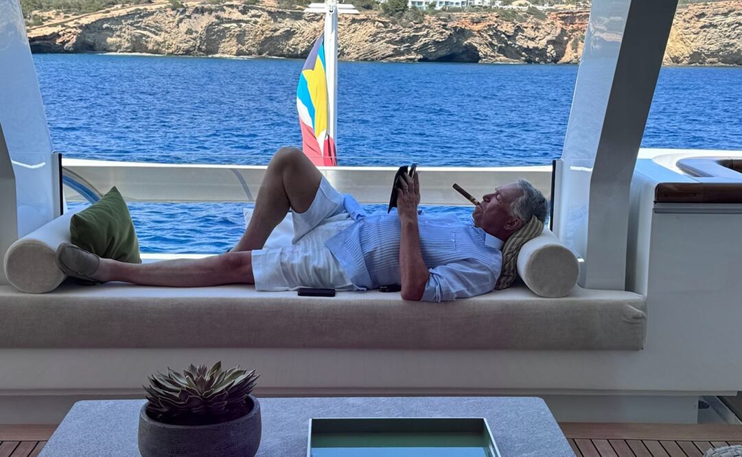 Salinas Pliego disfrutando de una relajante tarde en su lujoso yate, mientras se relaja fumando un puro y leyendo, con un impresionante paisaje marino de fondo. Foto: X