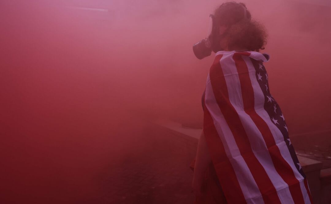 Un manifestante permanece de pie bajo la niebla de una granada de humo frente a una instalación del Servicio de Inmigración y Control de Aduanas (ICE) de Estados Unidos en el centro de Portland, Oregón (4/10/2025). Foto: Spencer Platt / AFP