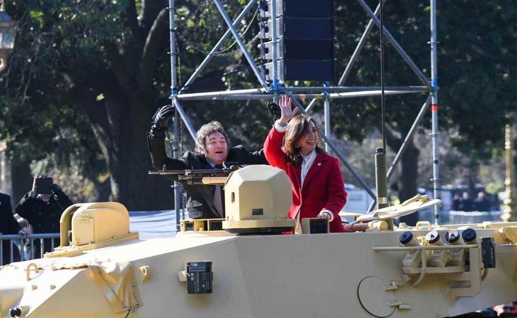 Momento en el que el presidente Milei y su vice, Victoria Villarruel, aprovecharon para bajar del palco y se subieron a uno de los blindados, saludando al público presente, mientras recorrían un tramo del desfile con todos sus custodios de seguridad caminando alrededor del vehículo. Foto: EFE