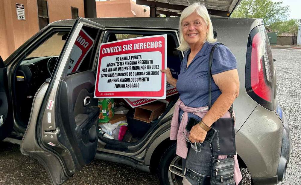 Gail Kocourek, una voluntaria del grupo humanitario Los Samaritanos, muestra una pancarta con información sobre derechos a migrantes que esperan ser procesados por la Patrulla Fronteriza el 21 de julio de 2025 al sur de Tucson, Arizona (EU). Ciudadanos estadounidenses del grupo humanitario Los Samaritanos, que distribuyen agua y ayuda a migrantes en el desierto entre Arizona y México, relataron a EFE la persecución y arresto que enfrentaron en marzo pasado de hombres armados, encubiertos, en carros sin insignias y sin orden judicial, que resultaron ser agentes migratorios de EU. Foto: EFE