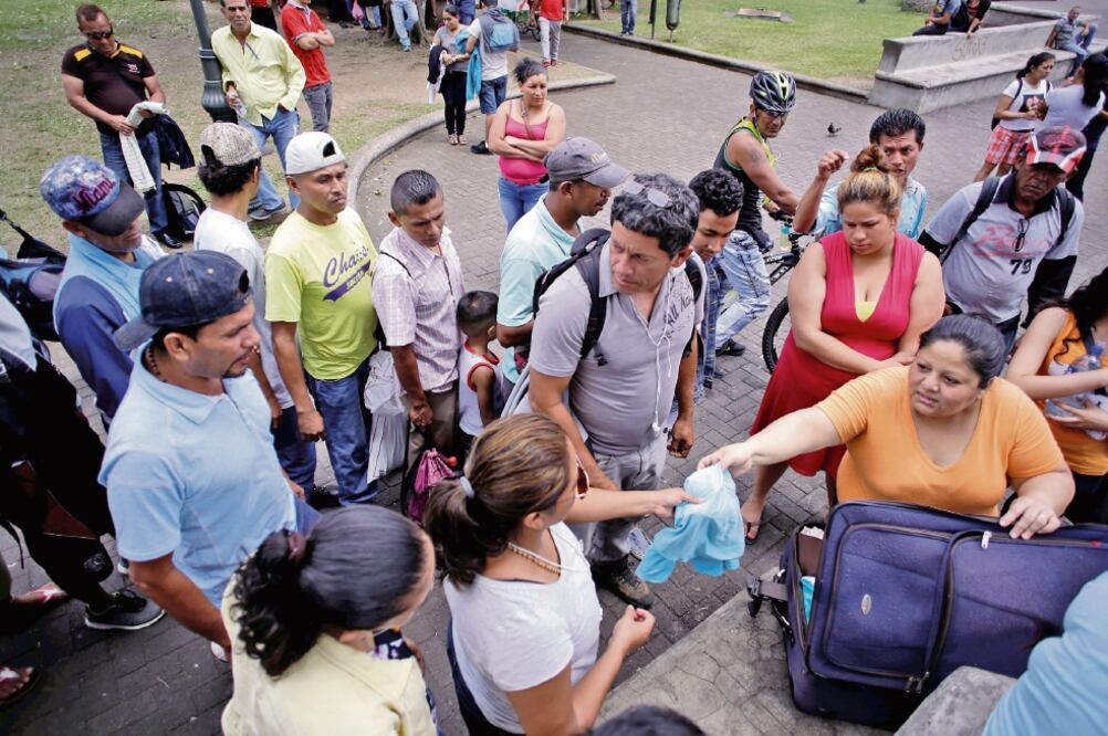 Una mujer distribuye ropa a nicaragüenses que huyeron de la violencia en su país y llegaron a San José, la capital costarricense (JUAN CARLOS ULATE. REUTERS)