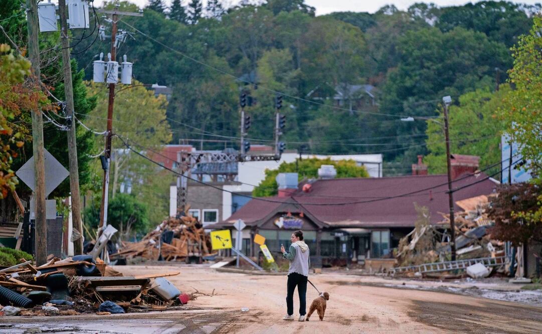 Mary Grace y su perro caminan por Biltmore Village, tras el paso del huracán Helene en Carolina del Norte, uno de los estados más afectados. Foto: AFP