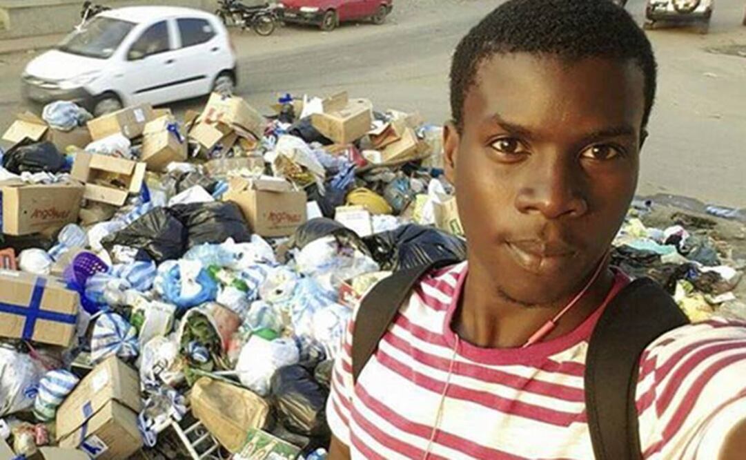 Un joven que posa delante de un montón de basura acumulada en una calle de Luanda. Foto: EFE