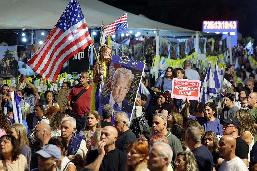 Personas ondean banderas estadounidenses y un retrato del presidente Donald Trump durante una reunión frente al Museo de Arte de Tel Aviv, conocido como la "Plaza de los Rehenes". Foto: AFP