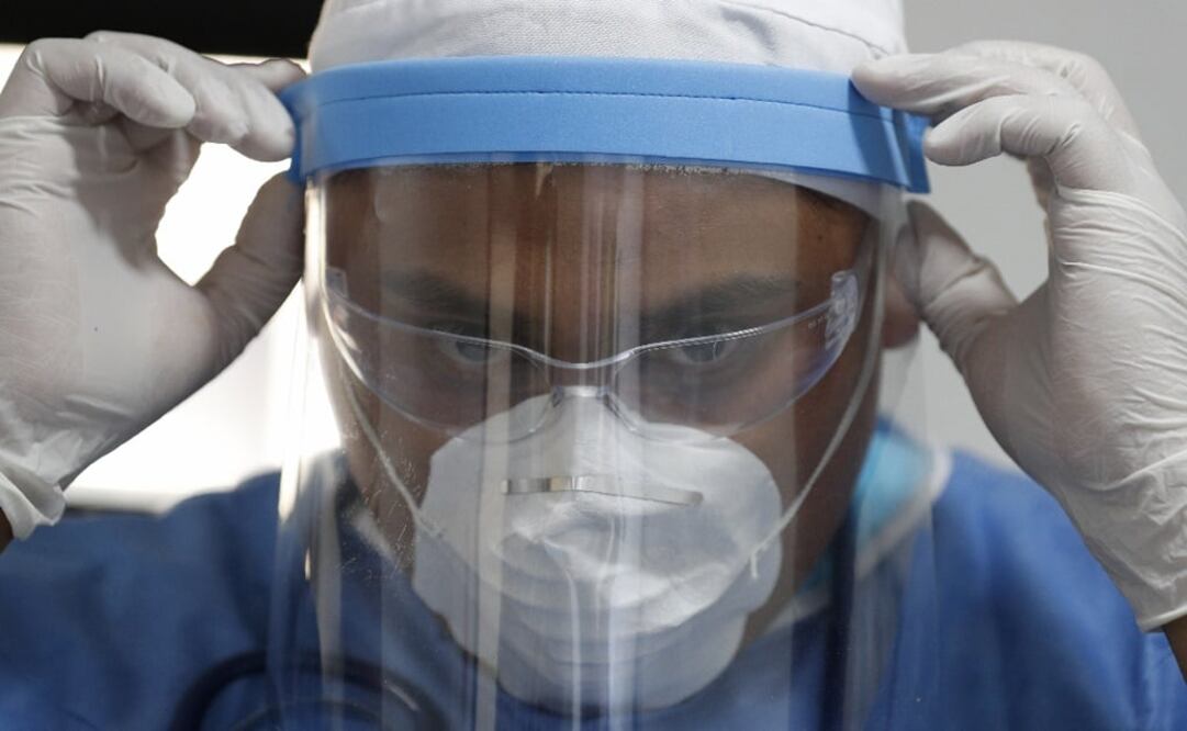 Nurse Giovanni Barragan adjusts his protective face shield inside a mobile health clinic – Photo: Rebecca Blackwell/AP