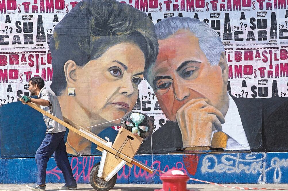 Un brasileño pasa con su carrito lleno de material para reciclar junto a un mural que muestra los retratos de la presidenta Dilma Rousseff y el vicepreside nte, Michel Temer, en Sao Paulo. Temer (ANDRE PENNER. AP)