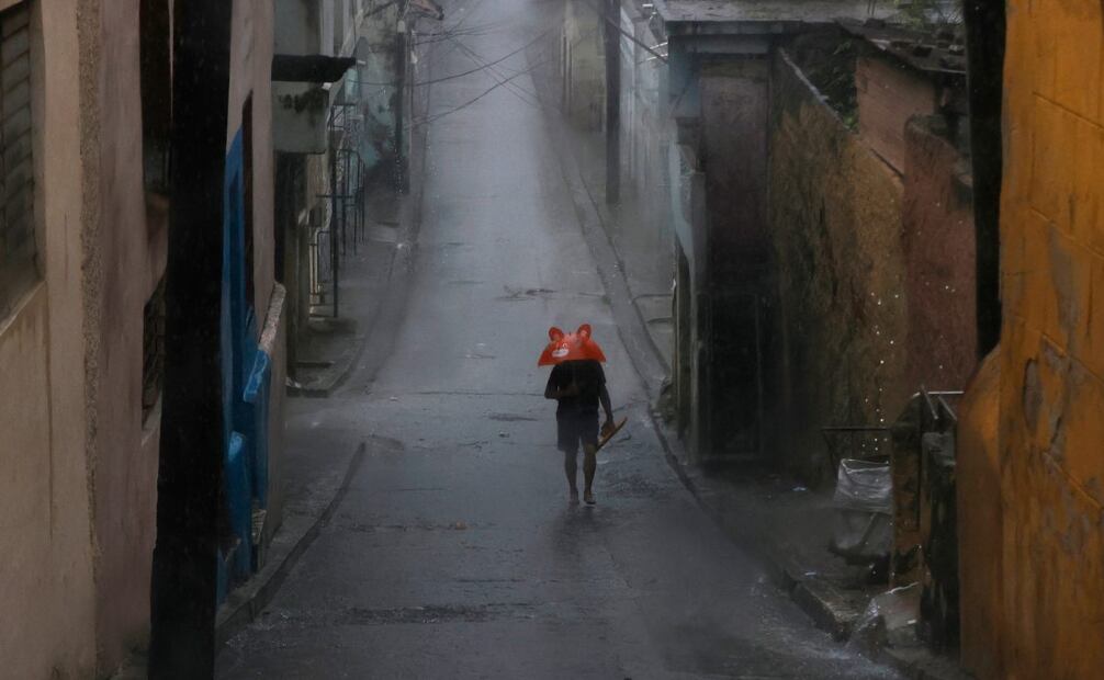 Una persona se protege de la lluvia este martes, en Santiago de Cuba (Cuba). El Instituto de Meteorología (Insmet) de Cuba prevé que Melissa impacte en su extremo oriental como un huracán "extremadamente peligroso", probablemente como un categoría 4 (de 5) en la escala Saffir-Simpson. (28/10/25) Foto: EFE
