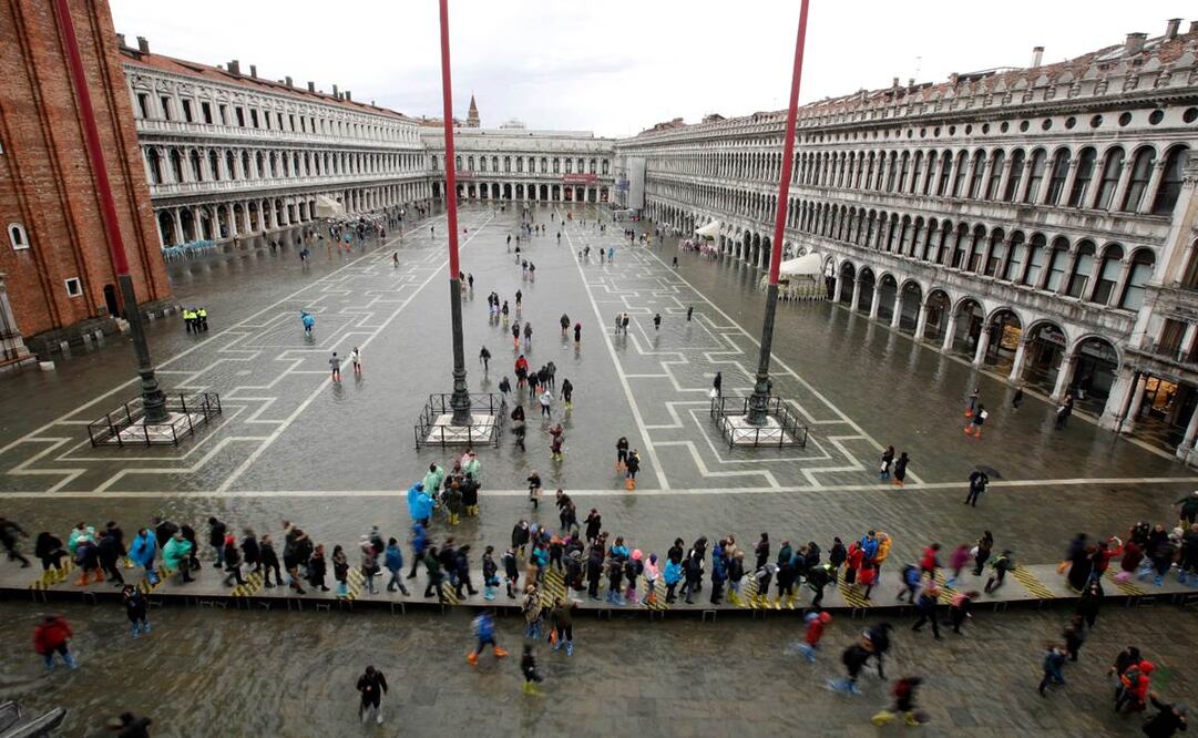 Gente caminando en una inundada Plaza de San Marcos en Venecia, Italia, el martes 12 de noviembre de 2019. (AP Foto/Luca Bruno)