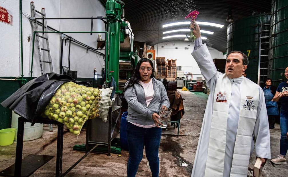 Un cura bendice la manzana que se cosechó durante el año, echa agua bendita sobre la máquina que lava y pica la manzana, y la prensa hidráulica que se encarga de sacar el jugo. Foto: Gabriel Pano / EL UNIVERSAL