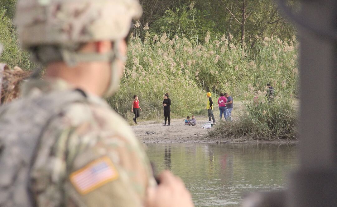 Un soldado estadounidense vigila a un grupo de personas que están del lado mexicano, en una zona en donde el río Grande divide ambos países. (THOMAS WATKINS. AFP)