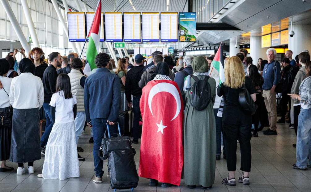 Una mujer con una bandera turca espera a los participantes de la «Marcha Global a Gaza» que parten del aeropuerto de Schiphol con destino a Egipto. Foto: EFE/EPA/Ramon van Flymen