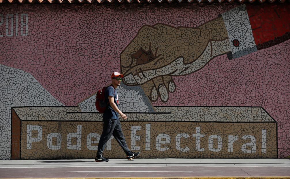 Un hombre camina junto a un mural que representa una urna, frente a la sede del Consejo Nacional Electoral en Caracas, Venezuela, tres días después de que el país enfrentara una controvertida elección presidencia. Foto: AP Foto/Cristian Hernández