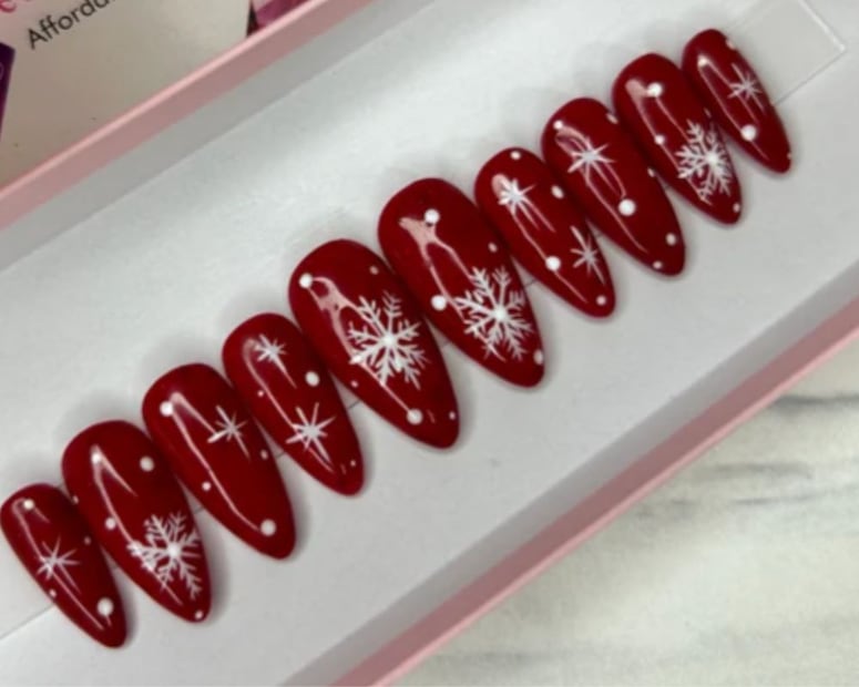 Las uñas rojas con copos de nieve crean un efecto reflectivo y muy elegante. Foto: Etsy