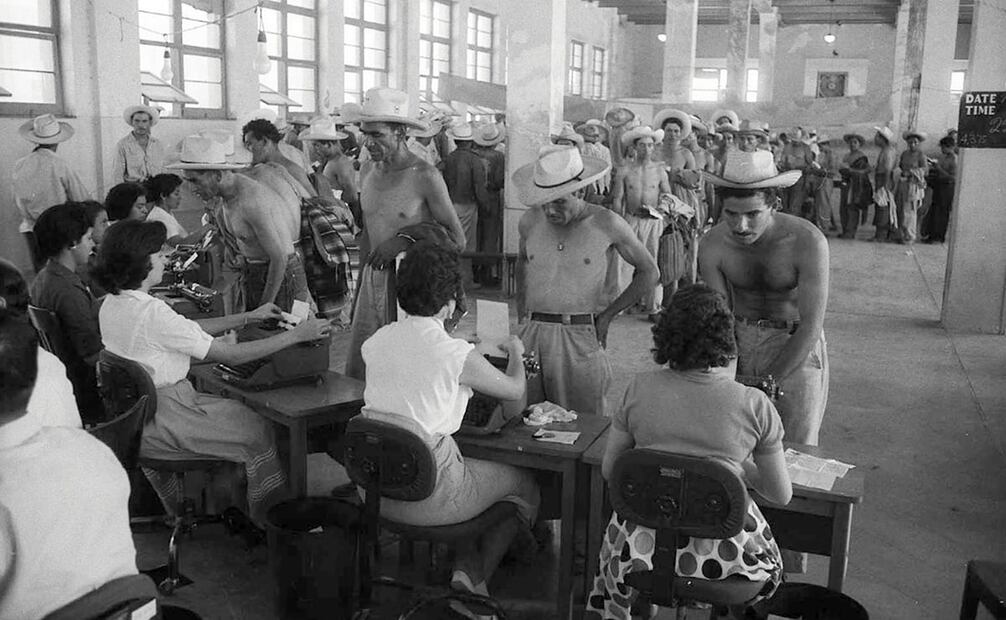 Después de su examen médico, los braceros dictan sus datos personales a un grupo de mecanógrafas en el Centro de Procesamiento de Monterrey. Foto: Leonard Nadel/National Museum of American History.