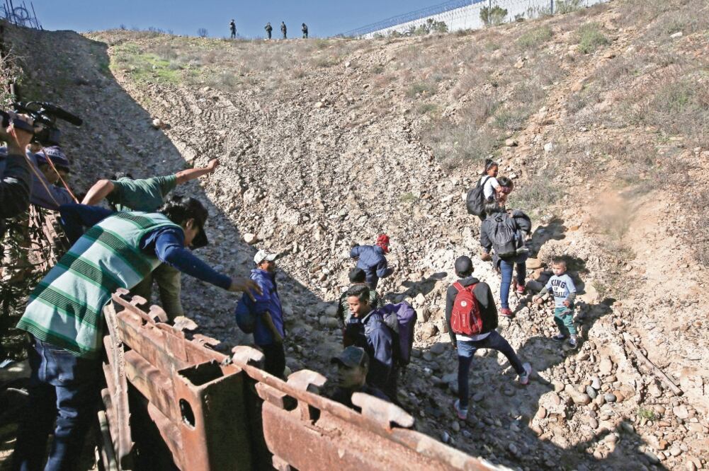 Migrantes hondureños cruzan la frontera entre México y Estados Unidos en Tijuana, para entregarse a la Patrulla Fronteriza estadounidense. MOISES CASTILLO. AP