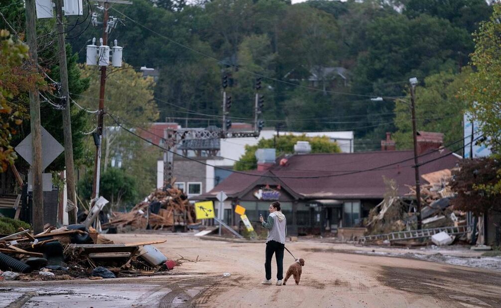 Mary Grace y su perro, Marley, caminan por Biltmore Village después del huracán Helene. Foto: AFP