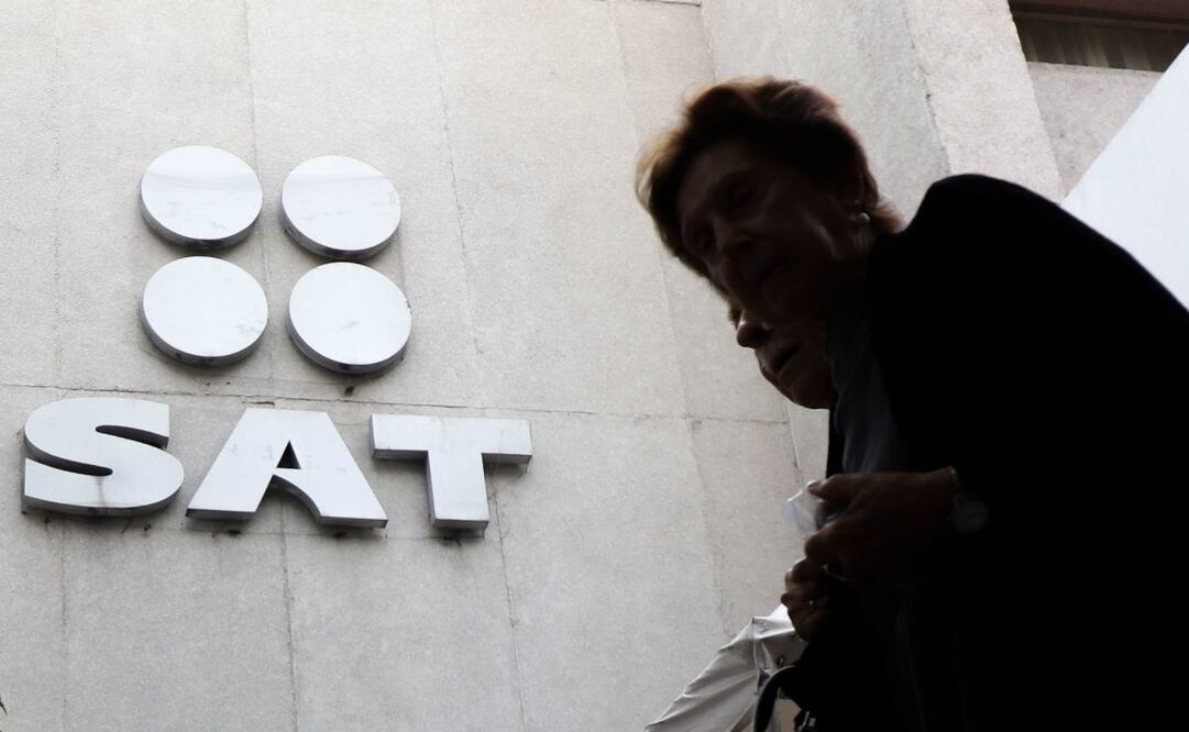 Dos personas caminan frente a las oficinas del SAT. FOTO: Cuartoscuro