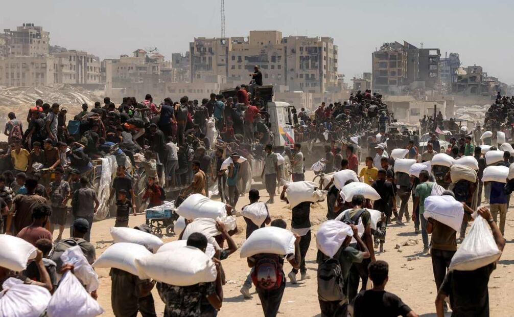 Personas caminan con sacos de harina entregados después de que camiones con ayuda humanitaria entraran al norte de Gaza el 27 de julio de 2025, procedentes del cruce fronterizo de Zikim. Foto: AFP