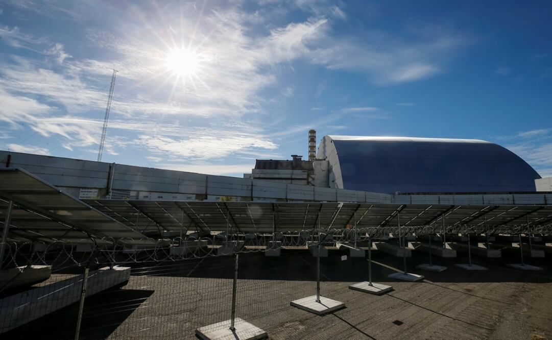 Solar panels are seen through barbed wire in front of the New Safe Confinement arch covering the damaged fourth reactor of the Chernobyl nuclear power plant - Photo: Gleb Garanich/REUTERS