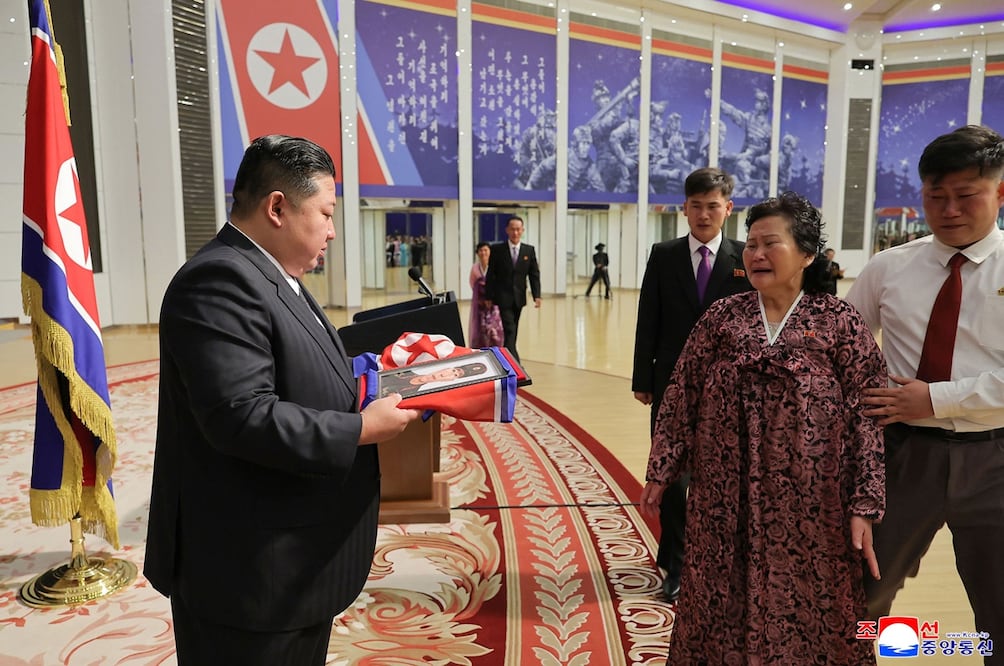 El líder norcoreano Kim Jong-un, al dar un retrato envuelto en la bandera norcoreana a la familia de un soldado, , en Pyongyang, que participó en operaciones militares en el extranjero. Foto: AFP
