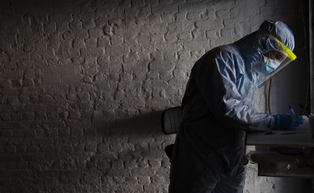 A doctor, wearing full protective equipment, takes notes as he screens a patient with symptoms of coronavirus - Photo: Francisco Seco/AP