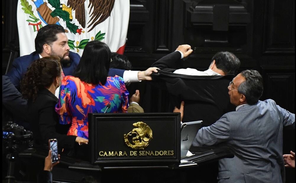 Antes de salir del salón de sesiones, el senador morenista también recibe un zape del diputado del PRI, Carlos Gutiérrez Mancilla, quien también lo jala de su chamarra y le lanza insultos. Foto: Cuartoscuro.com