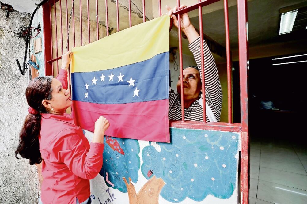 La maestra Virginia Barrera, candidata a la Constituyente por el barrio de Baruta, en Caracas coloca una bandera de su pais en una de las aulas. (JORGE SERRATOS. EL UNIVERSAL)