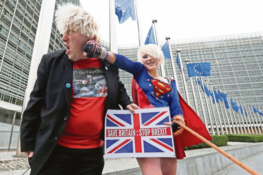Los activistas anti-Brexit Madeleina Kay, conocida como Superchica de la UE, y Drew Galdron, disfrazado de Boris Johnson, protestaron ayer en Bruselas. (YVES HERMAN. REUTERS)