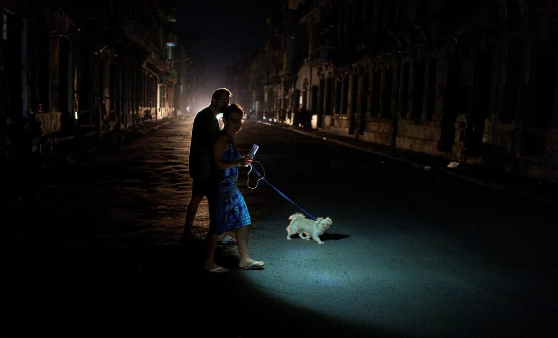 La gente enciende una linterna mientras cruza una calle con su perro durante un apagón en La Habana, el miércoles 10 de septiembre de 2025. Foto: AP