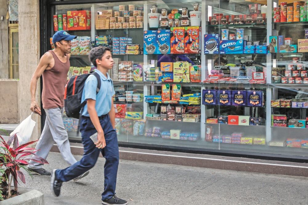 Venezolanos pasan junto a un super en Caracas. El gobierno de Maduro anunció aumento al salario, así como al bono alimentario. Foto/RAYNER PEÑA. EFE