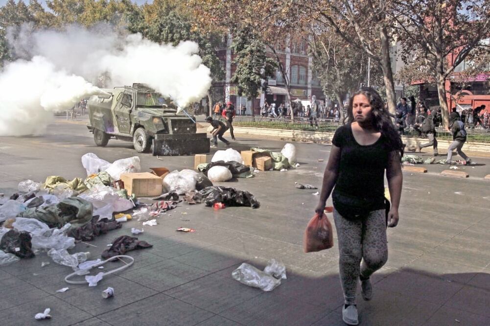 Una chilena pasa donde un grupo de manifestantes se enfrentó contra los policías en Santiago (LUIS HIDALGO. AP)