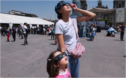 Visitantes observan eclipse solar desde la explanada del Zócalo de la CDMX