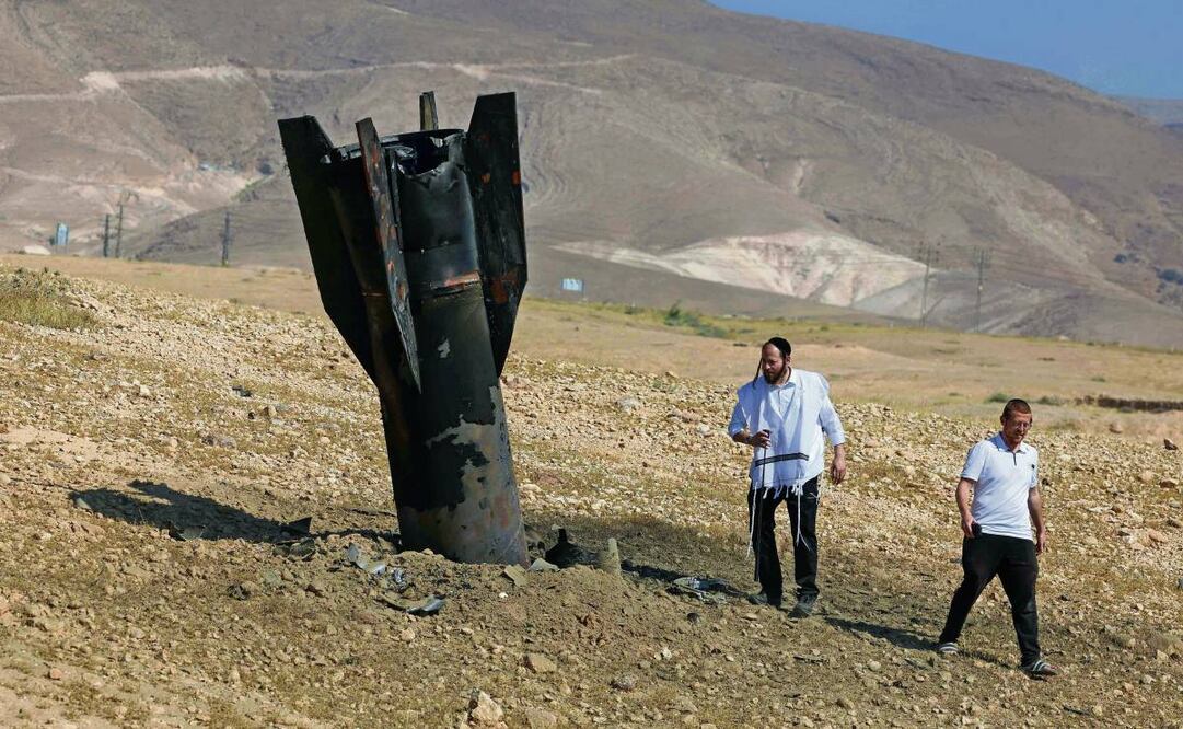 Dos hombres inspeccionan un cohete a las afueras de Jericó, en Israel, luego de ataques de Irán y de los rebeldes hutíes en Yemen. Foto: Ahmad Gharabli / AFP