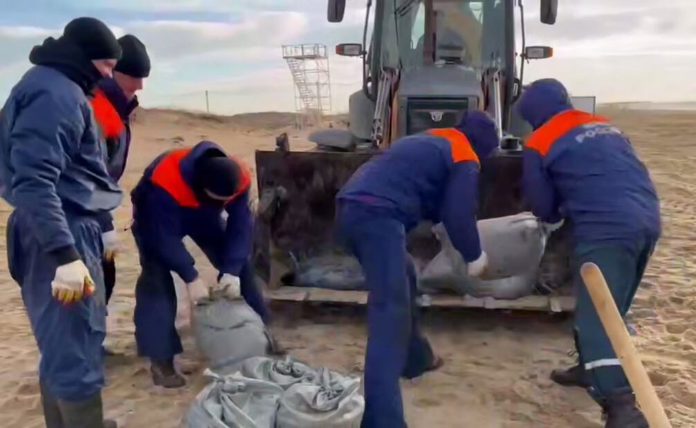 Una imagen fija extraída de un vídeo distribuido por el servicio de prensa del Ministerio de Situaciones de Emergencia de Rusia muestra a empleados del Ministerio de Situaciones de Emergencia de Rusia recogiendo arena de playa empapada de petróleo durante una operación de limpieza en el estrecho de Kerch, en la región de Krasnodar. Rusia, 21 de diciembre de 2024. Según el departamento del Ministerio de Emergencias de Rusia en Crimea, los petroleros Volgoneft-212 y Volgoneft-239 chocaron durante una tormenta el 15 de diciembre. 2024, provocando un derrame de petróleo en el Mar Negro. Foto: EFE
