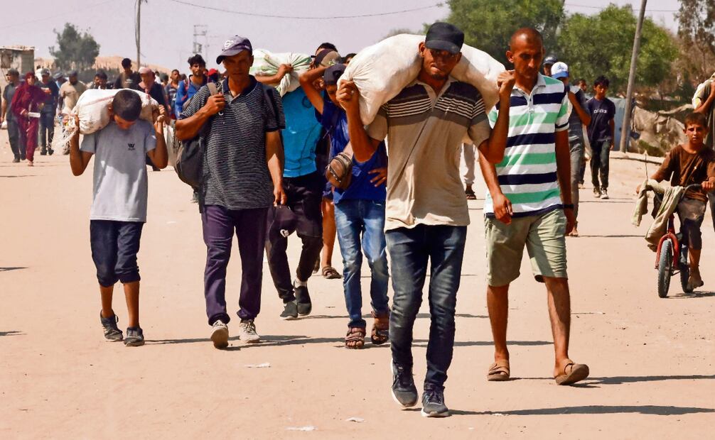 Palestinos ayer, al llevar la ayuda humanitaria recibida en el corredor de Rafah mientras caminan por la zona de Mawasi, en el sur de la Franja de Gaza. Foto: AFP