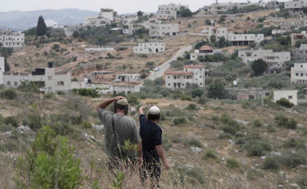 Colonos israelíes miran hacia el pueblo vecino a la mañana siguiente de que Tzeela Gez, que iba camino del hospital para dar a luz, fuera asesinada en un ataque a las afueras del asentamiento de Bruchin, en Cisjordania, el 15 de mayo de 2025. Foto: AP