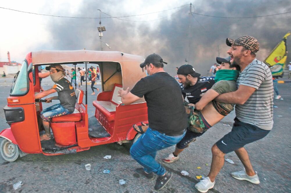 Manifestantes iraquíes ayudan a un hombre herido durante las protestas contra el gobierno en Bagdad. Foto/AHMAD AL-RUBAYE. AFP