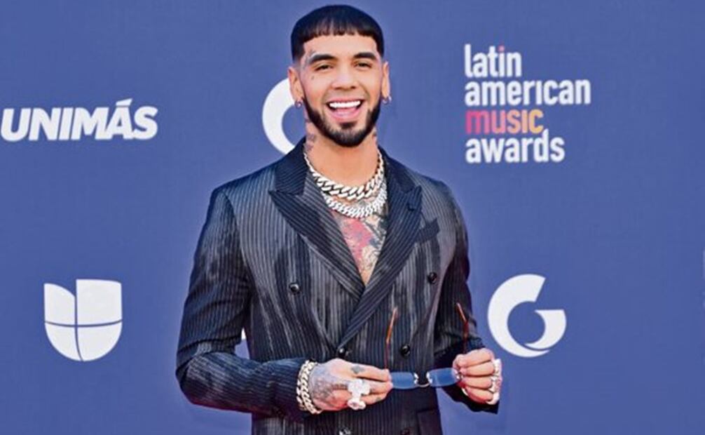 Anuel AA, sonriente, con traje a rayas deslavado, Foto: AP Y AFP