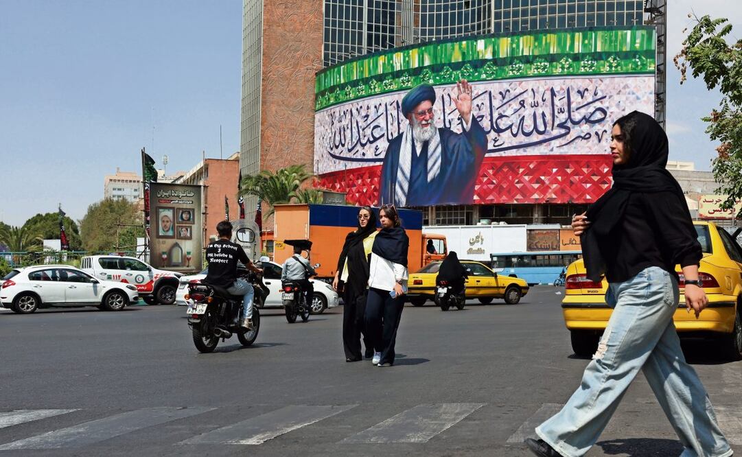 Iraníes caminan junto a una imagen del ayatola Ali Khamenei sobre una bandera iraní, en la plaza Valiasr de Teherán. Foto: EFE