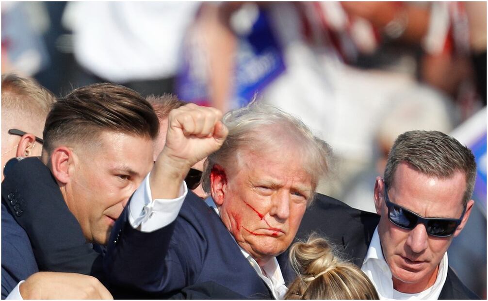 Donald Trump se retira del lugar, resguardo por el Servicio Secreto, después de ser víctima de un atentado. Foto: David Maxwell/EFE